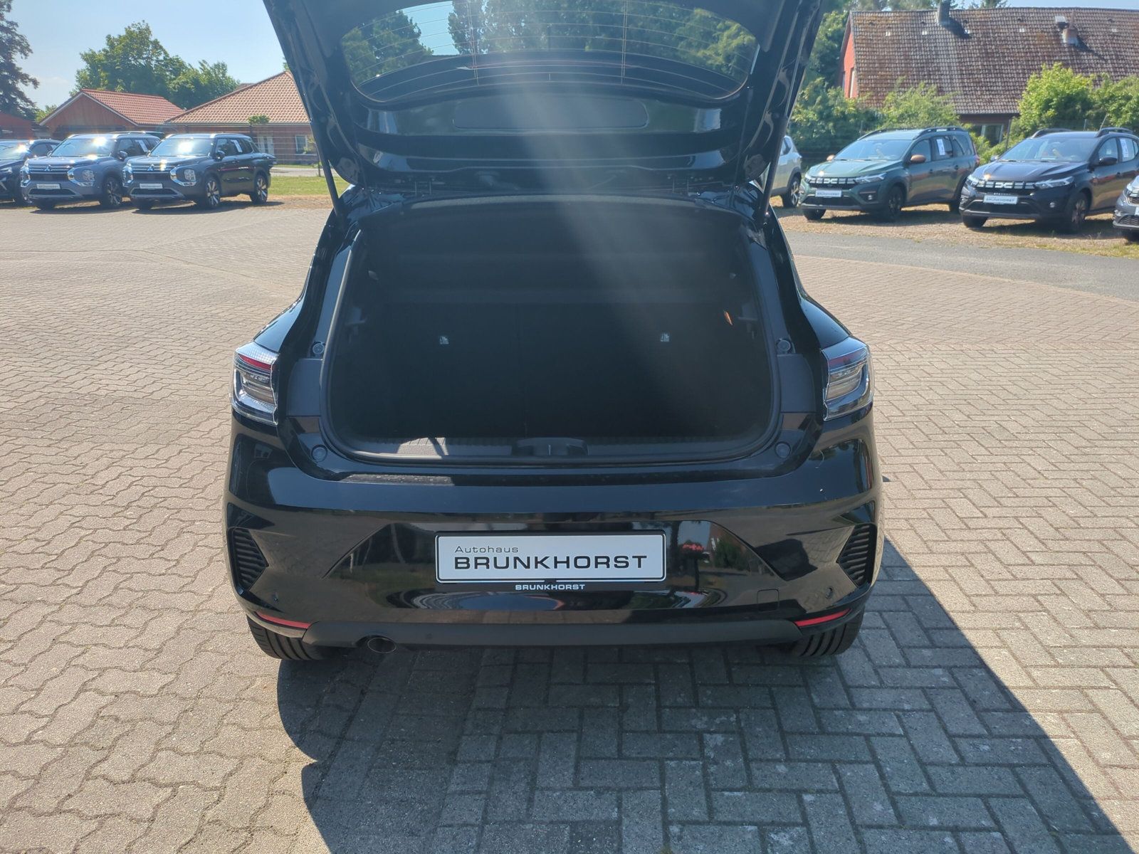 Schwarzer Kompaktwagen mit geöffneter Heckklappe im modernen Autohaus Brunkhorst Showroom mit eleganter LED-Deckenbeleuchtung und Stadtpanorama im Hintergrund