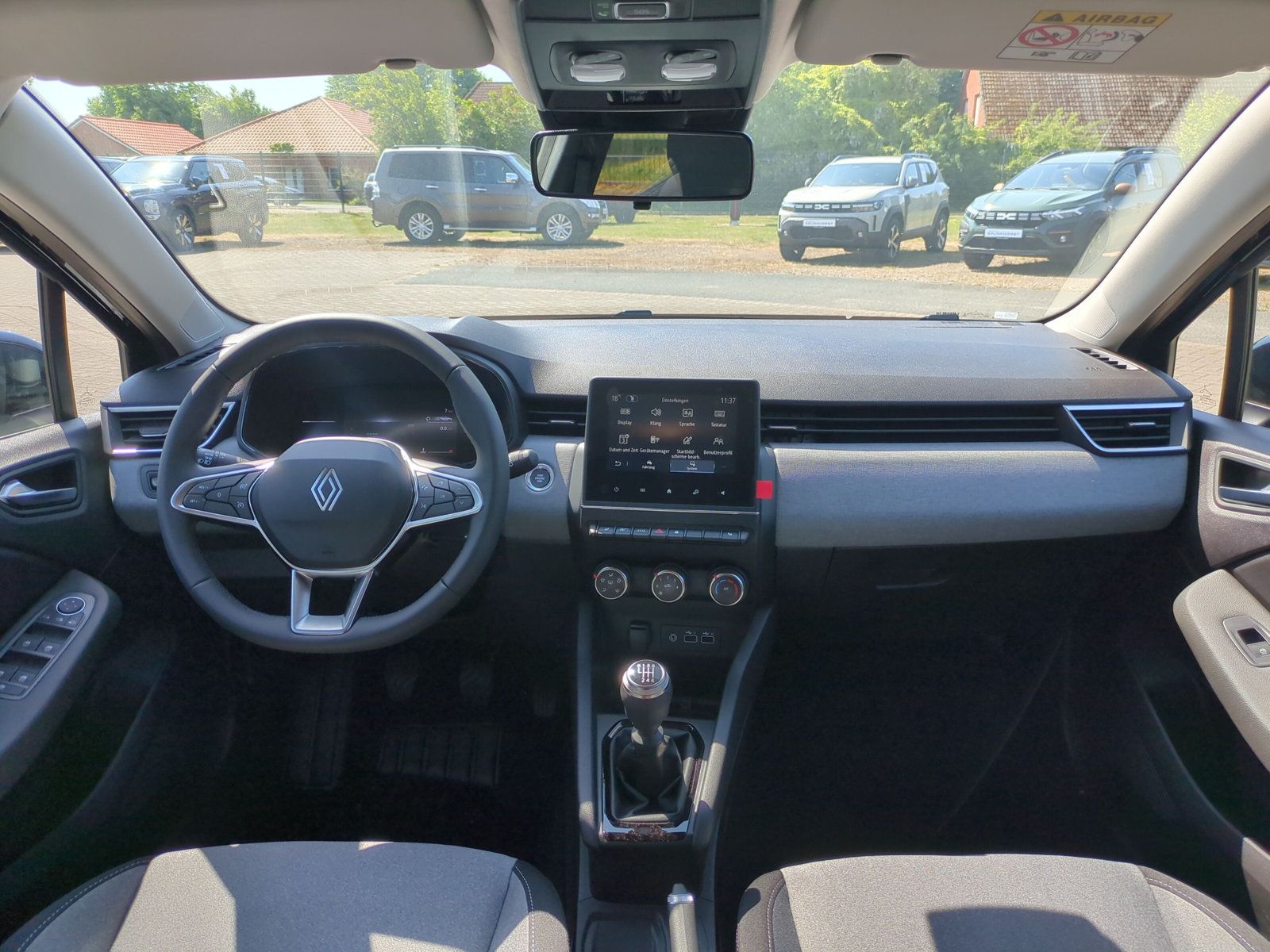 Innenraum des Renault Clio mit modernem Cockpit, digitalem Tacho, Touchscreen-Infotainmentsystem, Schaltgetriebe und zweifarbigen Sitzen in schwarz-beige im Autohaus-Showroom