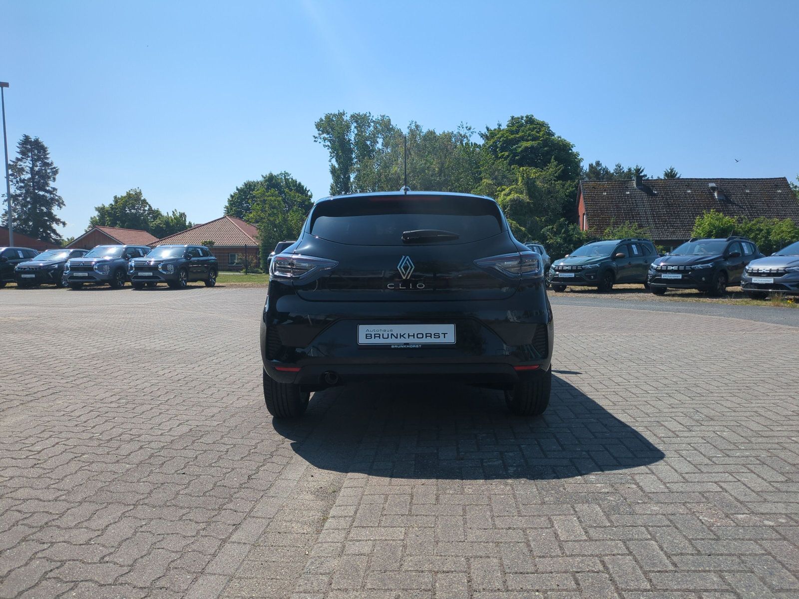 Schwarzer Renault Clio Heckansicht im modernen Autohaus Brunkhorst Showroom mit beleuchteten Renault-Logos und großen Glasfenstern