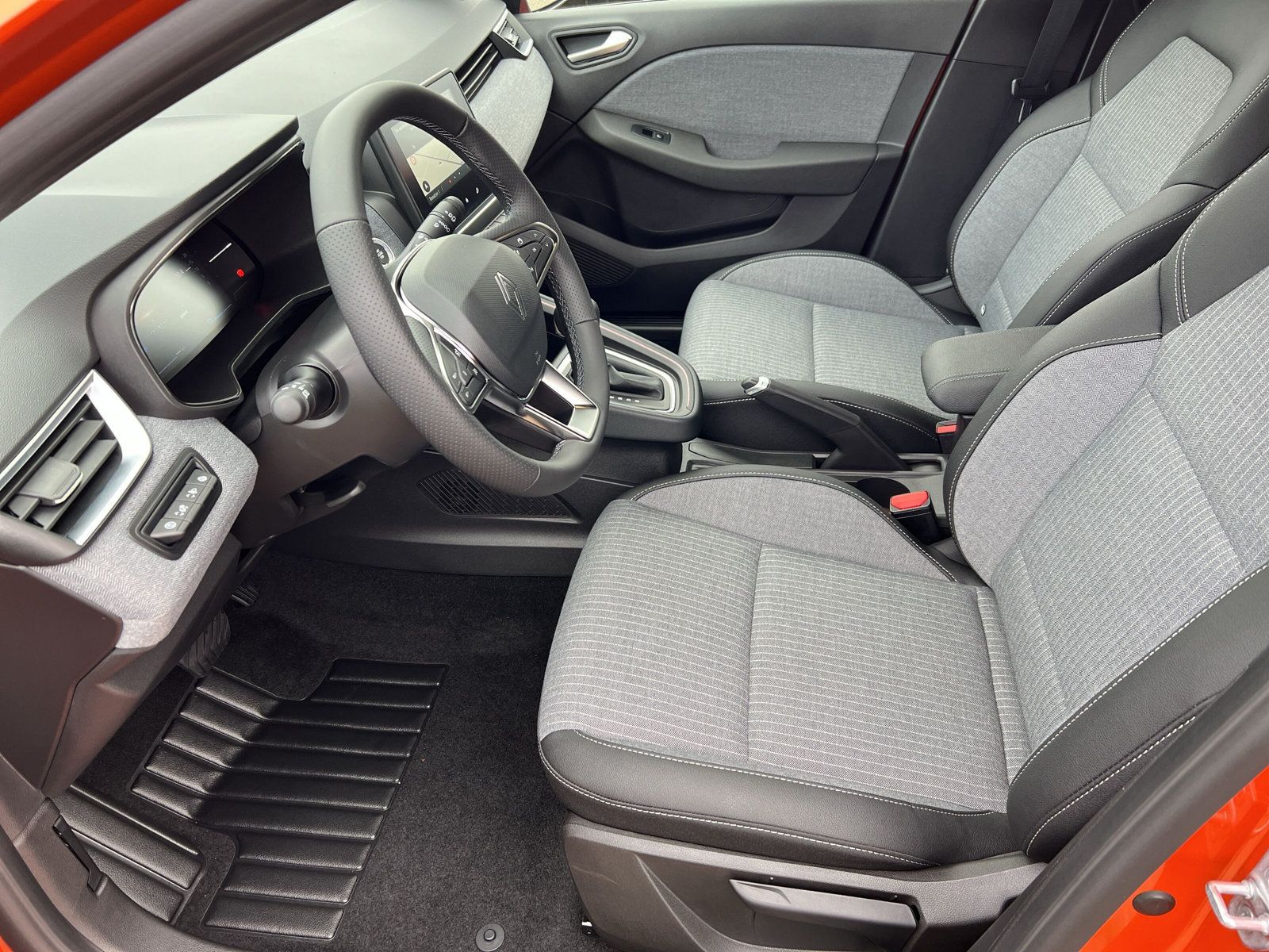 Innenraum Renault Captur mit grau-schwarzen Stoffsitzen, digitalem Cockpit, Multifunktionslenkrad und modernem Armaturenbrett im Autohaus