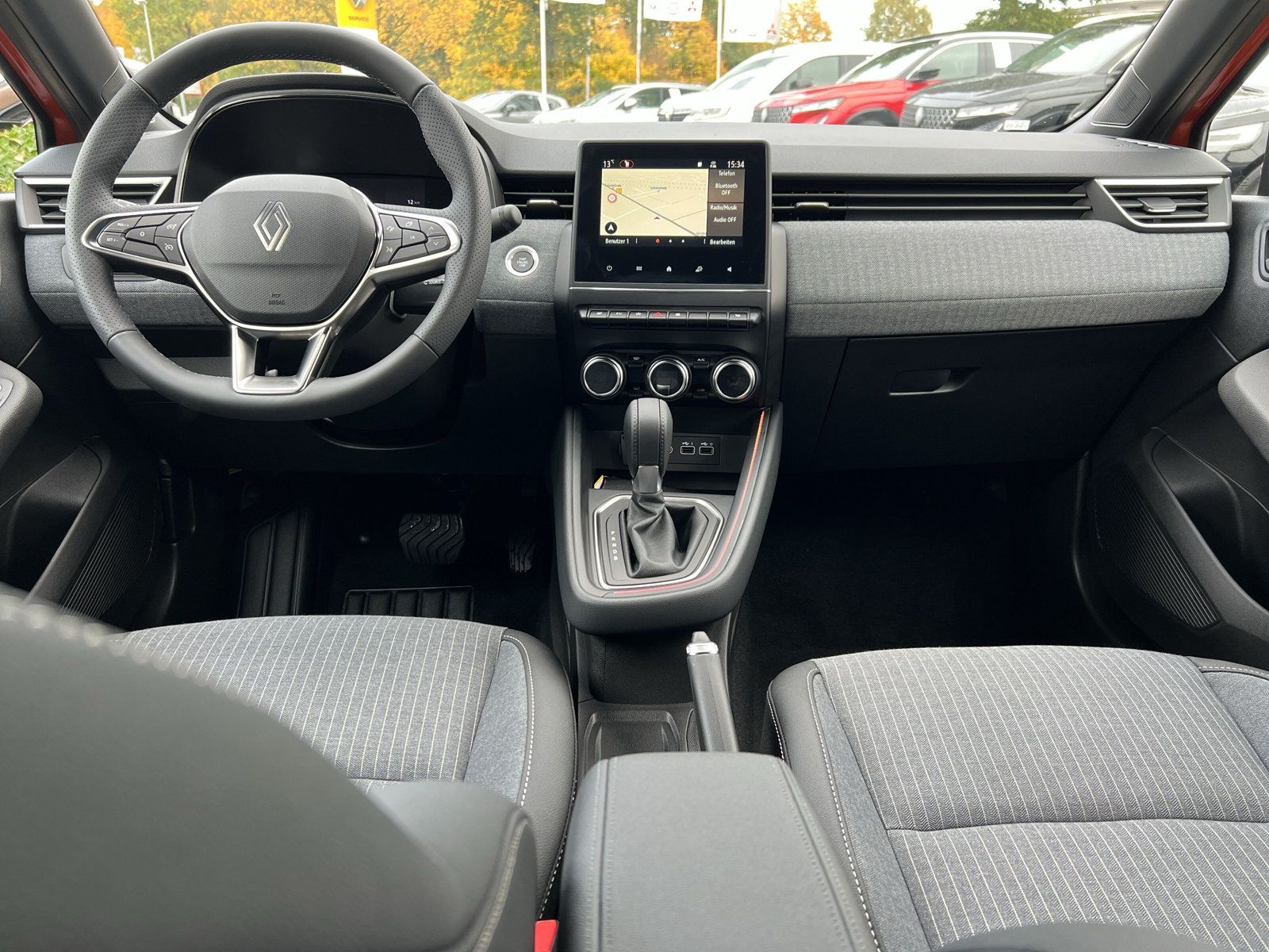 Renault Clio Innenraum mit Cockpit, Lenkrad, Infotainment-Touchscreen mit Navigation, manuellem Schaltgetriebe und grauem Stoffinterieur im Autohaus