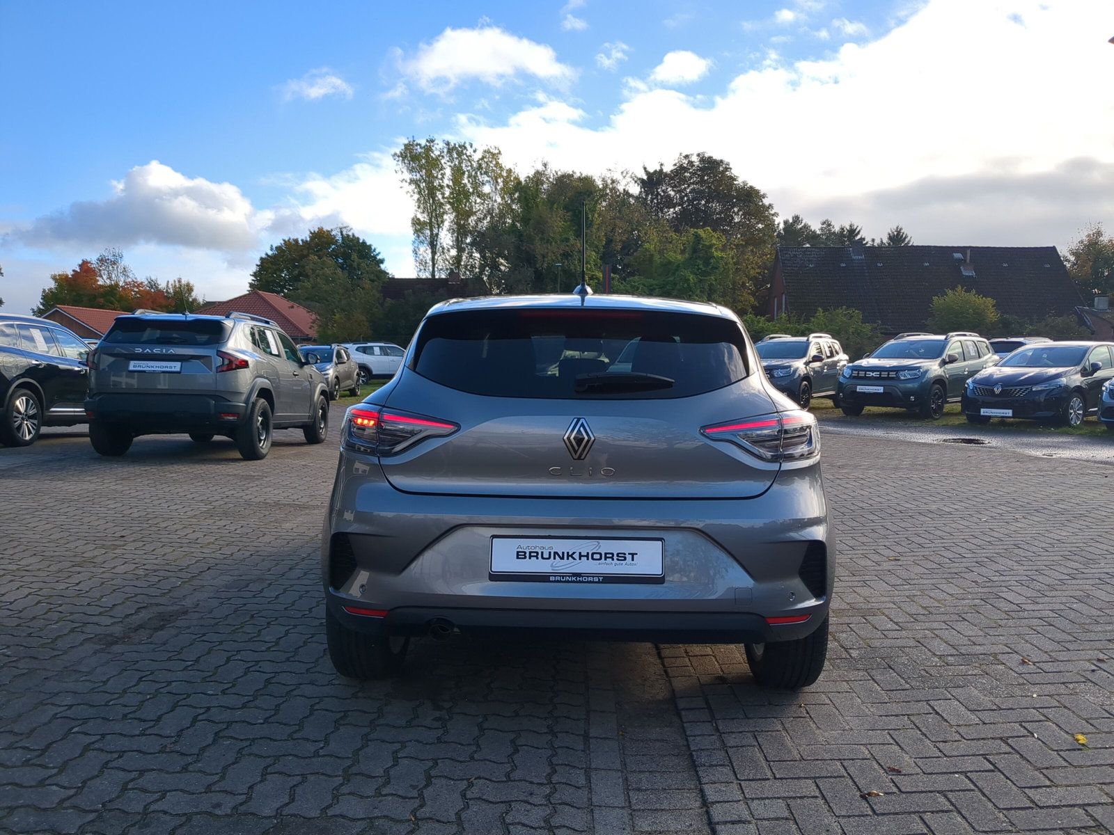 Grauer Renault Clio Heckansicht im modernen Autohaus Bruijn & Horst Showroom mit großen Glasfenstern und eleganter Beleuchtung