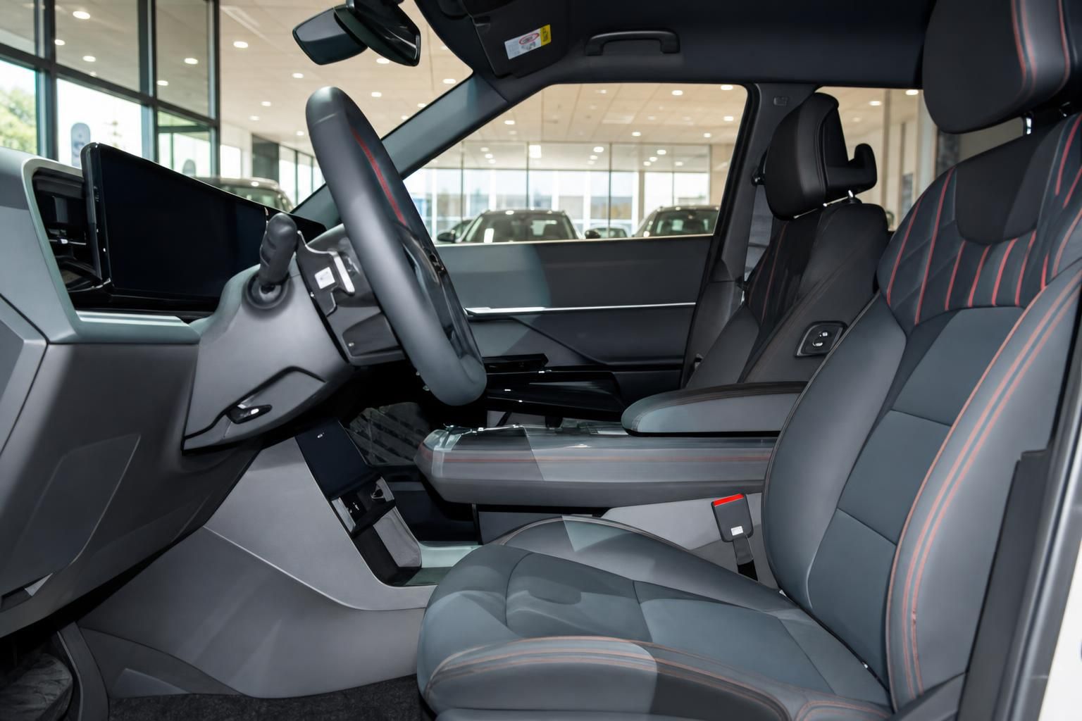 Fahrzeug Innenraum mit schwarzen Sportsitzen, roten Ziernähten, Lenkrad und digitalem Cockpit im Autohaus