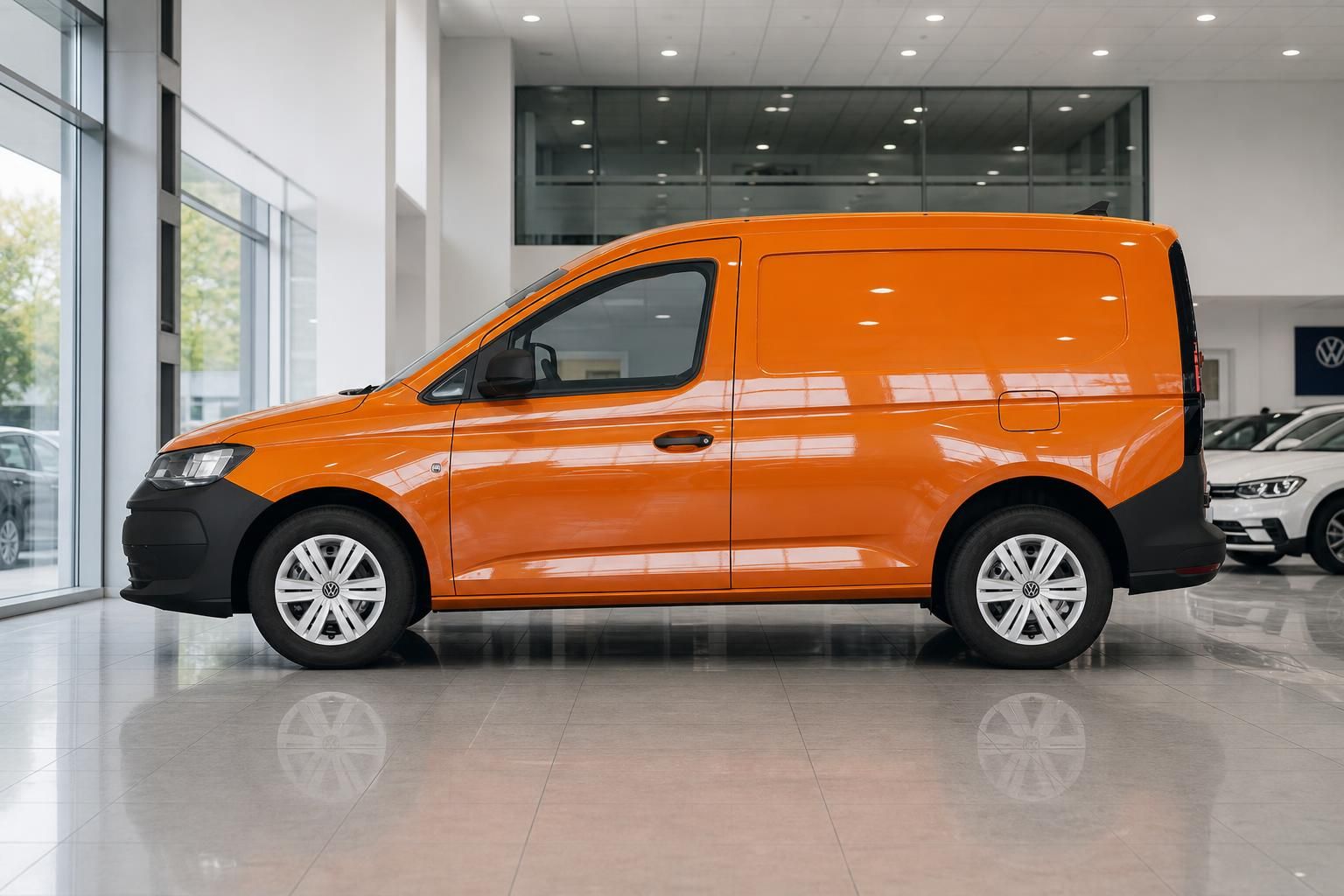 VW Caddy Kastenwagen orange Seitenansicht im Autohaus Showroom