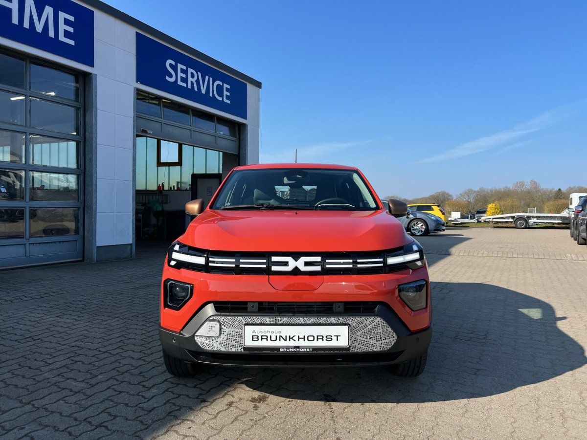 Dacia Spring Elektroauto Frontansicht in Orange - Kompakter SUV im Autohaus Showroom