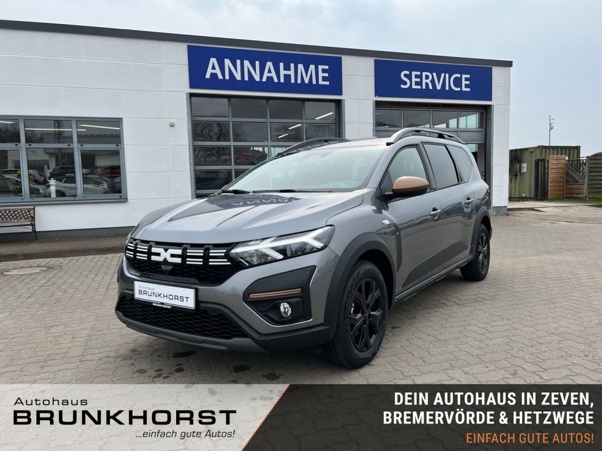 Dacia Jogger grau metallic Seitenansicht im Autohaus-Showroom mit schwarzen Felgen
