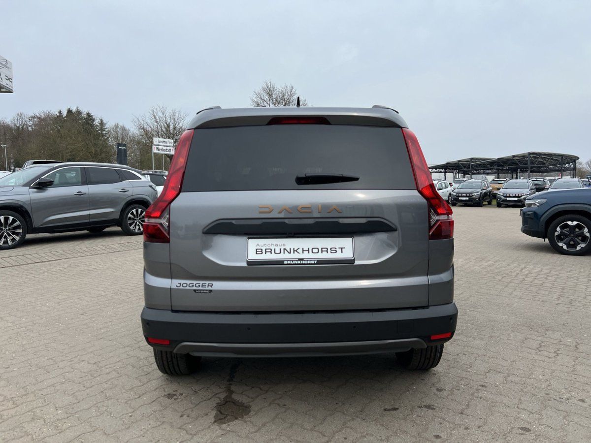Dacia Jogger Heckansicht grau metallic mit Hybrid-Badge im Autohaus-Showroom