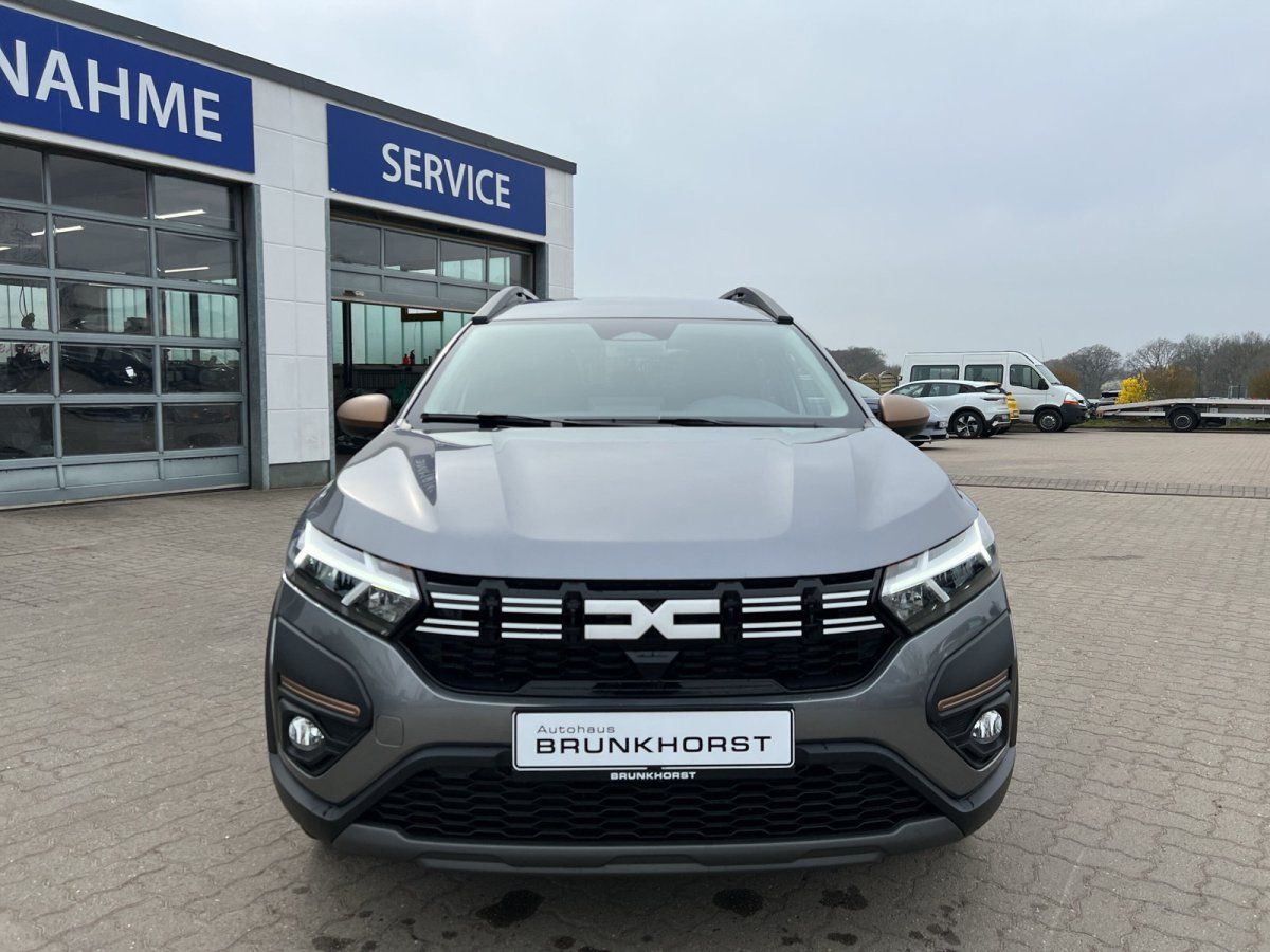 Dacia Jogger Frontansicht grau metallic mit schwarzem Kühlergrill im Autohaus-Showroom