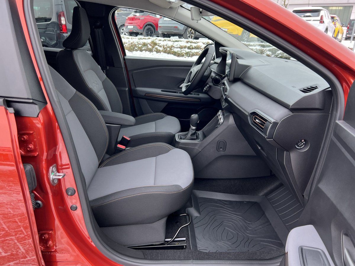 Innenraum rotes Fahrzeug mit grauen Stoffsitzen, Schaltgetriebe und Gummimatten Beifahrerseite