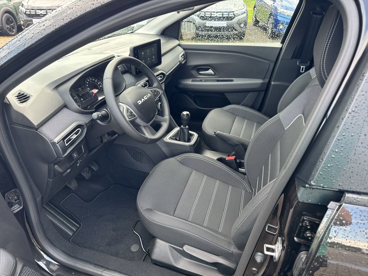 Dacia Innenraum Fahrersitz mit Lenkrad, Infotainment-Display und Schaltgetriebe in Schwarz