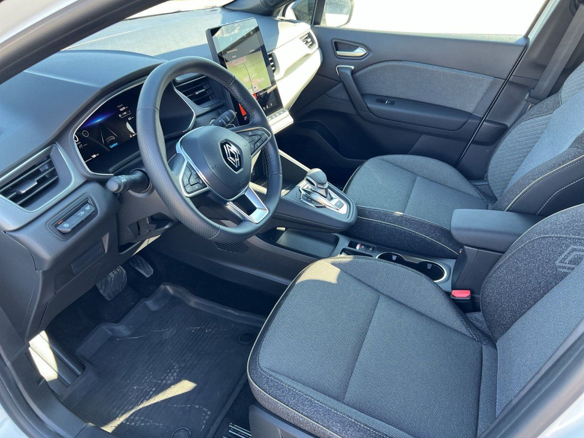 Renault Innenraum mit Lenkrad, Touchscreen-Navigation und grauen Stoffsitzen im Autohaus