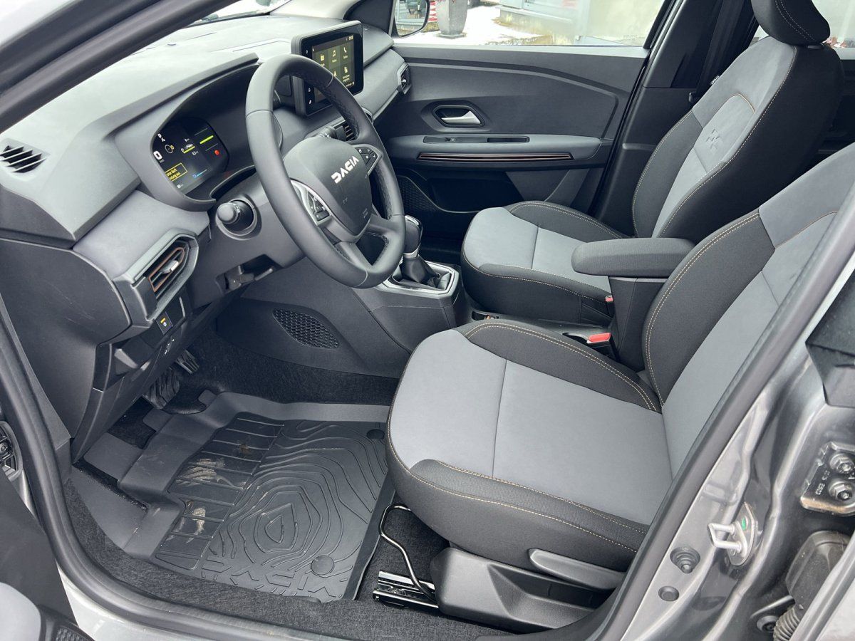 Dacia Innenraum Fahrerseite mit digitalem Cockpit, Lenkrad und Stoffsitzen in Grau-Schwarz