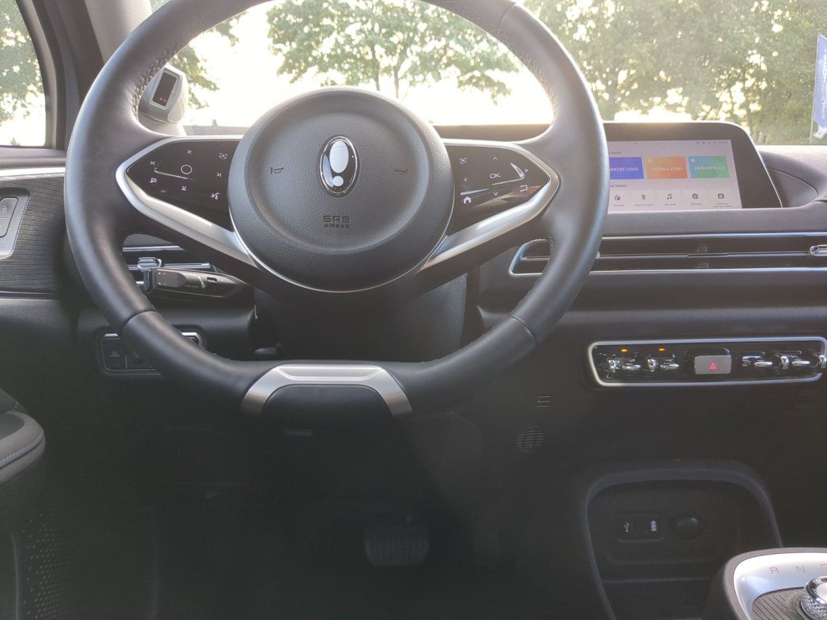 Innenraum eines modernen Elektrofahrzeugs mit Lenkrad und großem Infotainment-Display im Autohaus