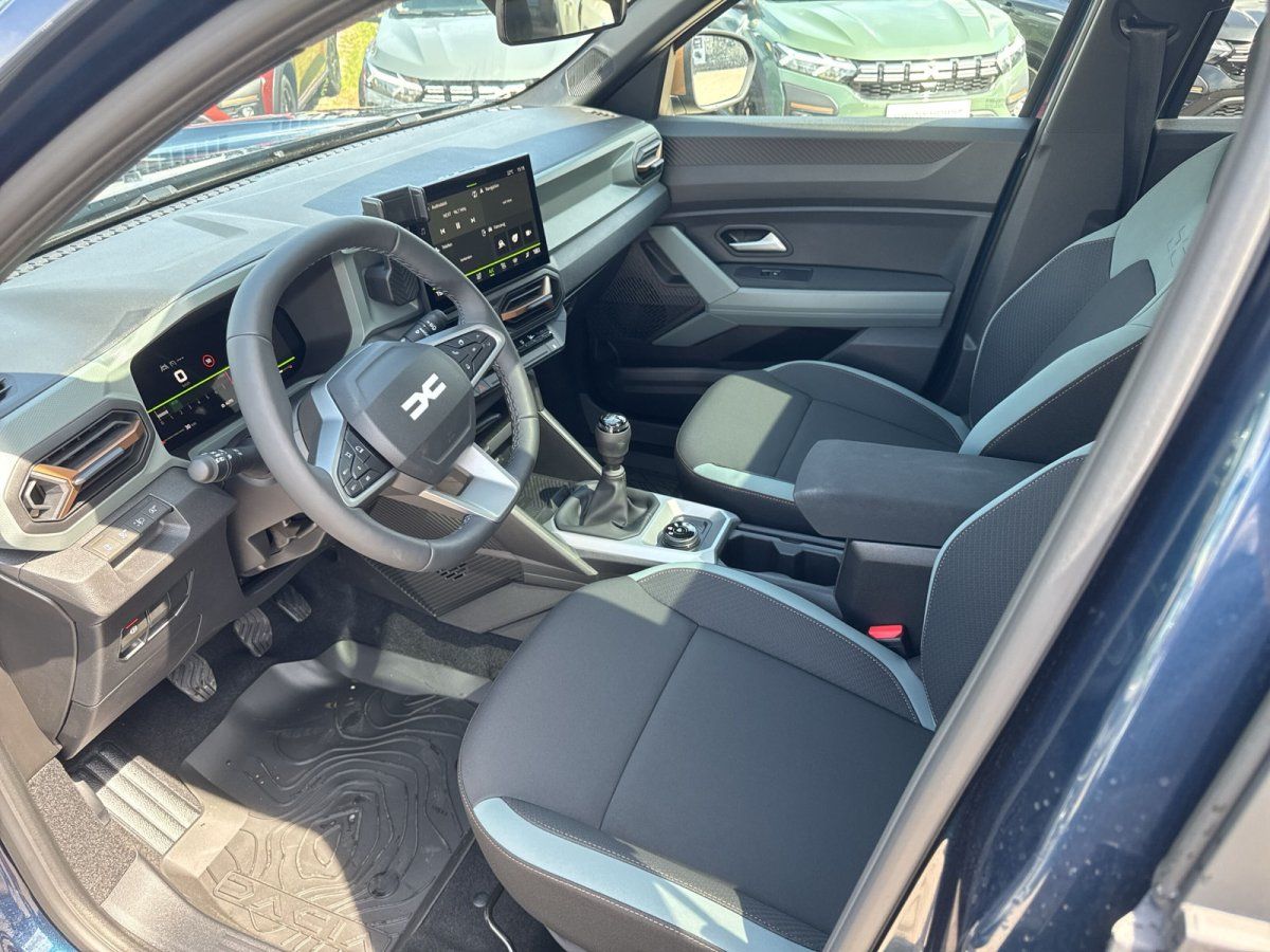 Dacia Innenraum mit Lederlenkrad, Infotainment-Display und Schaltgetriebe in modernem SUV