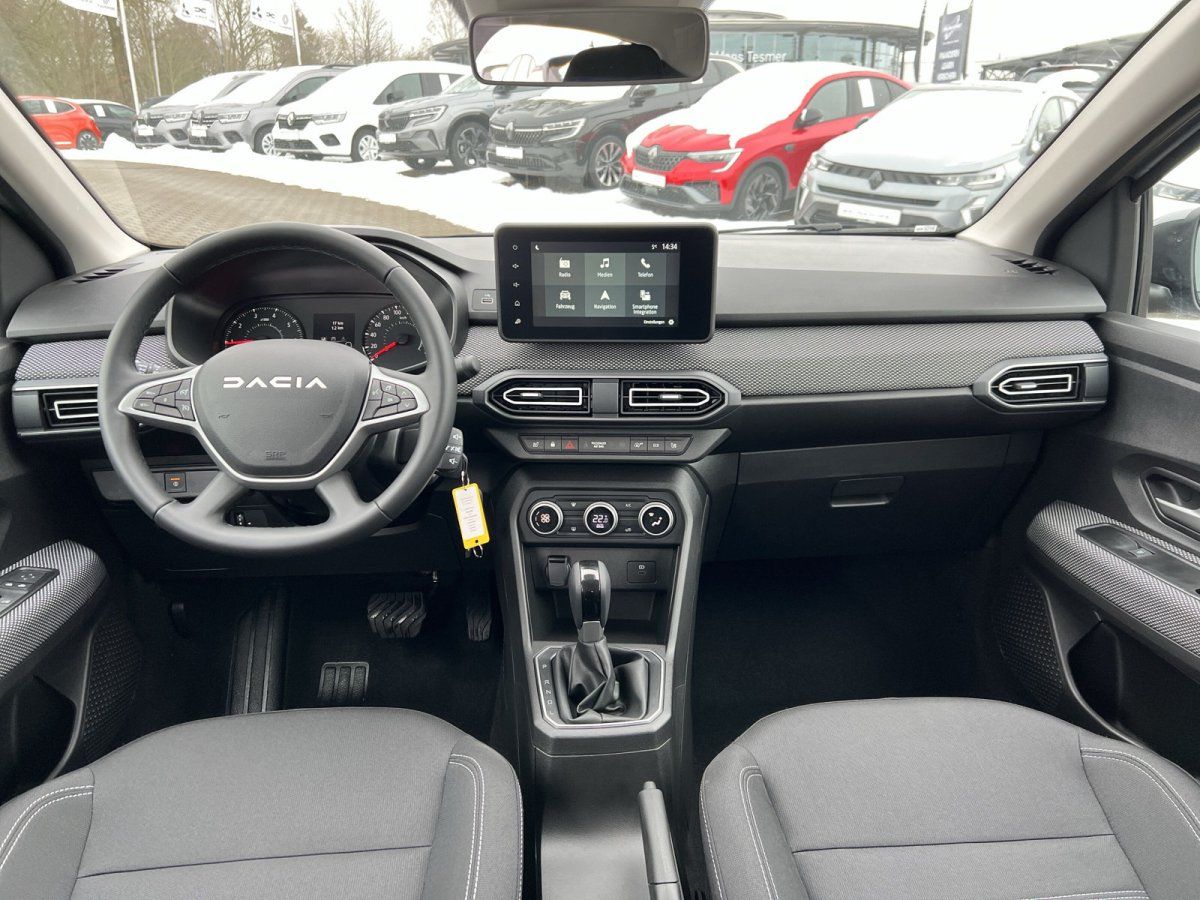 Dacia Innenraum mit Touchscreen, Lederlenkrad und grauem Stoff-Interieur im Autohaus