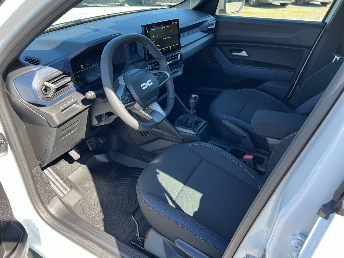 Dacia Innenraum mit Lenkrad, Touchscreen und blauen Stoffsitzen – Cockpit Nahaufnahme