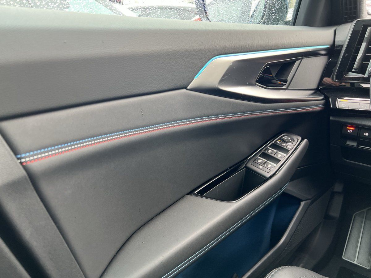 Fahrzeuginnenraum Fahrertür mit Fensterheber und blauer Ambientebeleuchtung im Autohaus