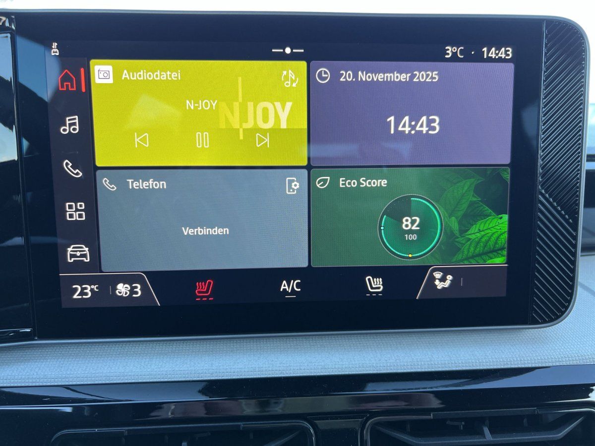 Innenraum-Cockpit mit Infotainment-Display in einem VW Autohaus mit Neuwagen im Hintergrund