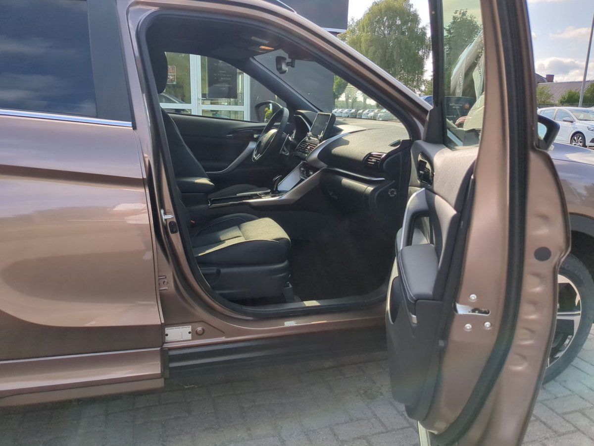 Innenraum eines bronze-braunen Fahrzeugs mit geöffneter Beifahrertür und schwarzer Lederausstattung beim Händler