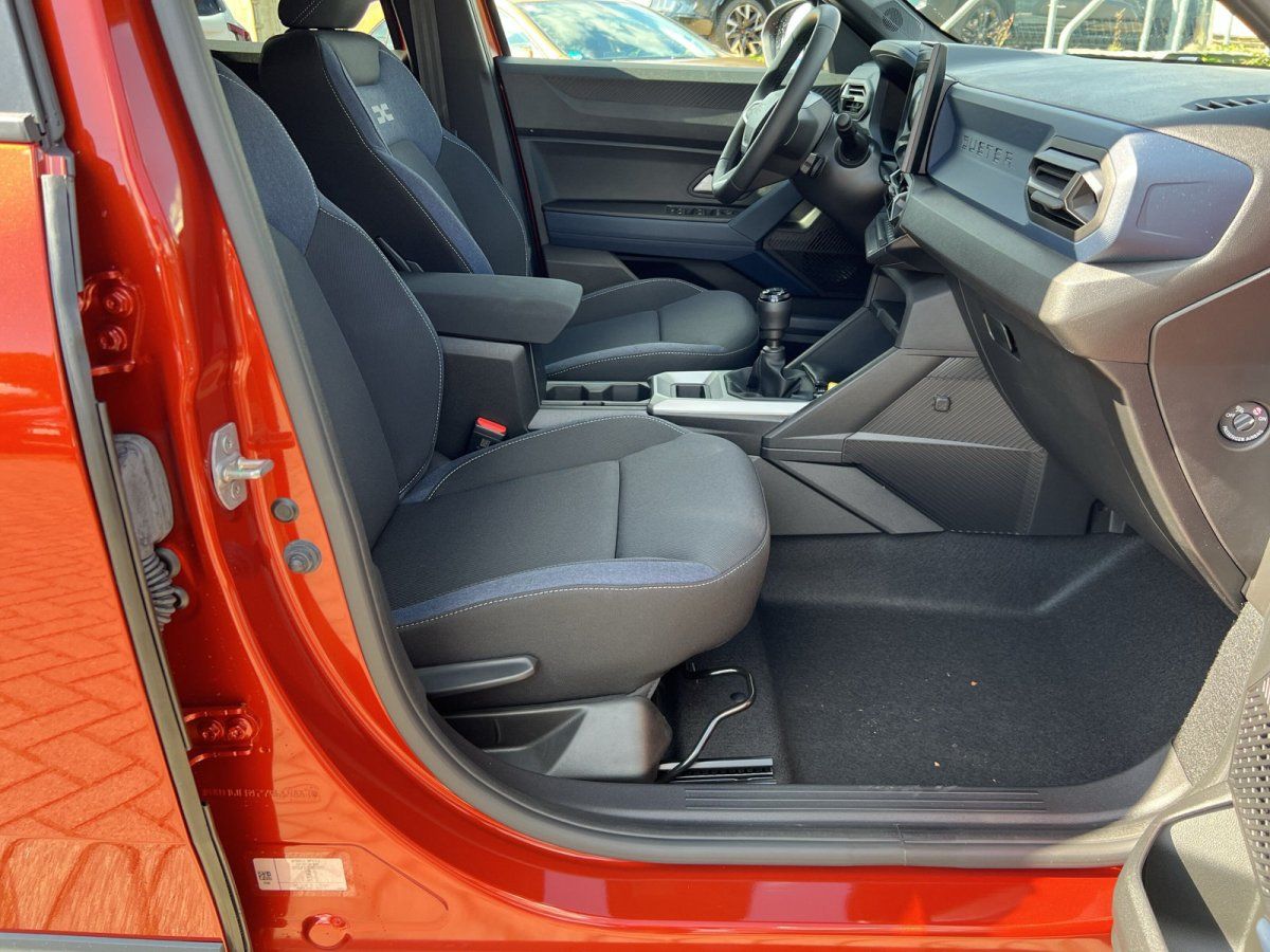 Dacia Innenraum Fahrersitz und Mittelkonsole mit Schaltgetriebe in orangenem Fahrzeug im Autohaus