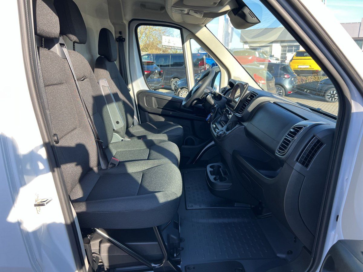 Innenraum eines weißen Transporter-Vans mit Doppelkabine, dunklen Stoffsitzen und moderner Mittelkonsole