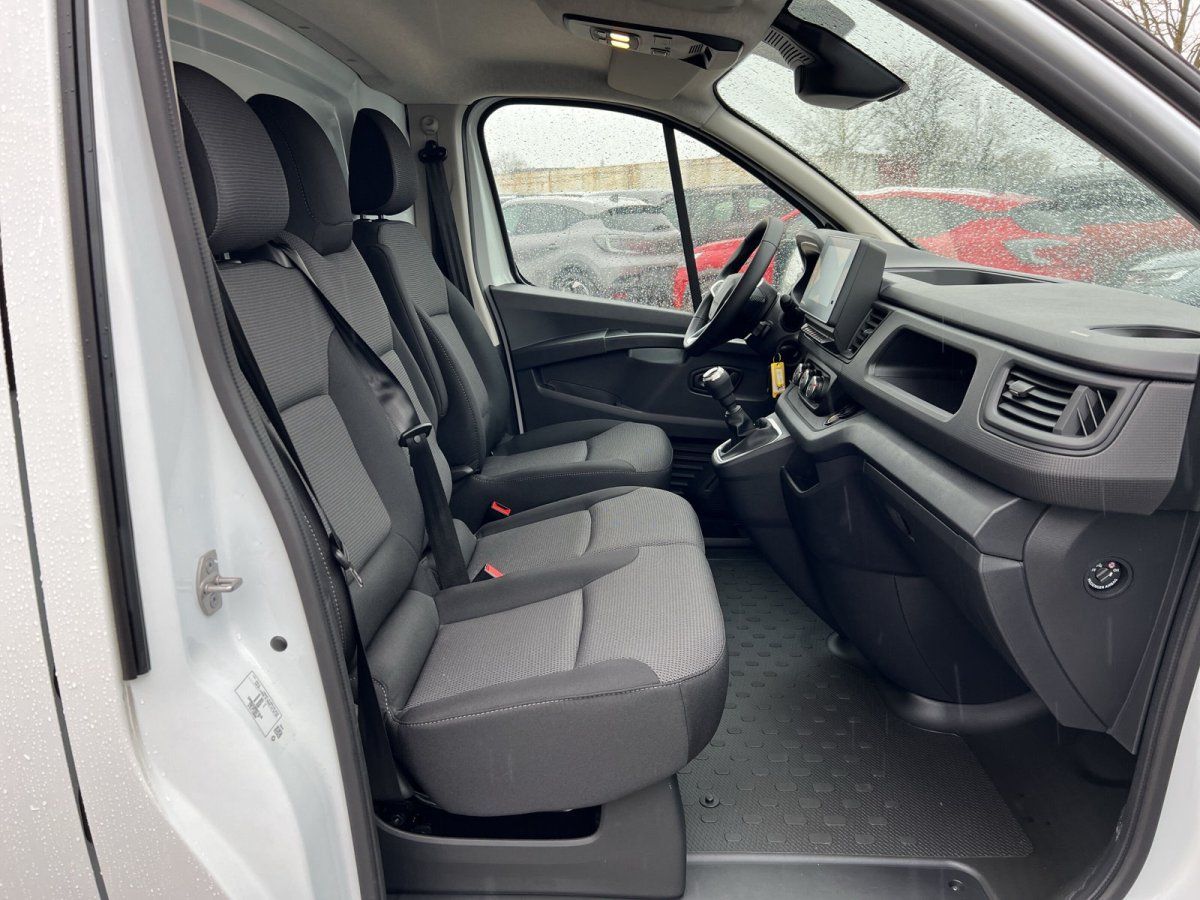 Innenraum eines weißen Transporters mit grauen Stofssitzen und Schaltgetriebe