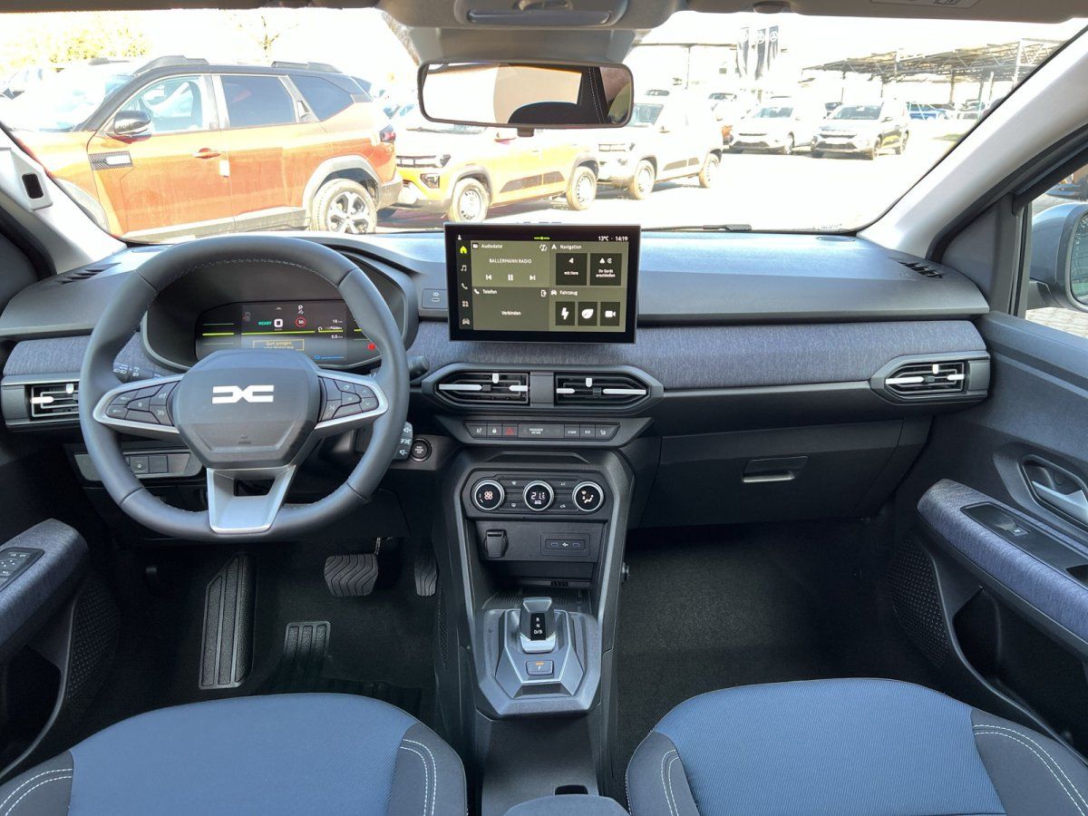 Dacia Innenraum mit digitalem Cockpit, Touchscreen und blauen Sitzen im Autohaus