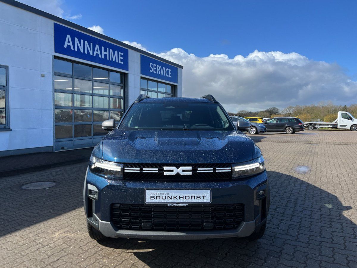 Frontansicht eines blauen Dacia SUV mit modernem Design im Autohaus-Showroom