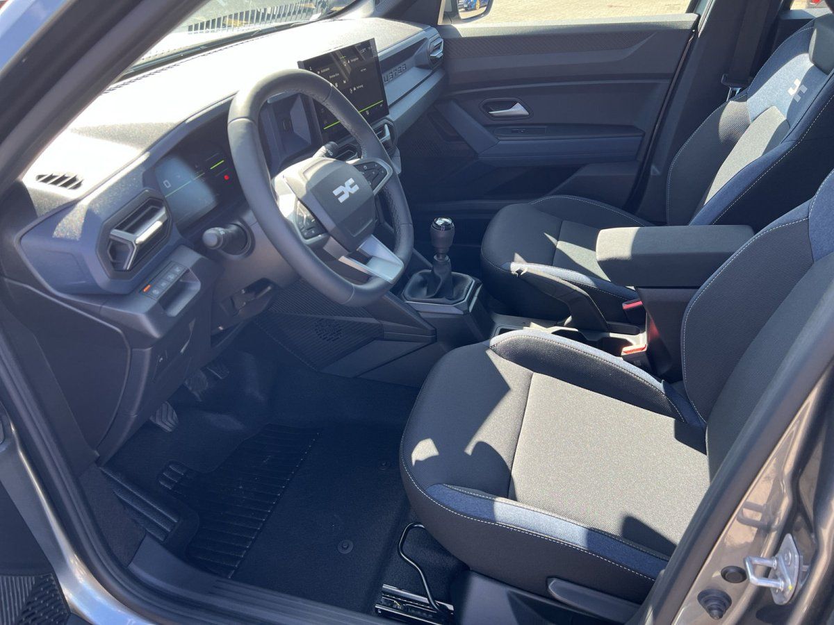 Dacia Innenraum mit schwarzen Stoffsitzen, Schaltgetriebe und modernem Infotainment-Display
