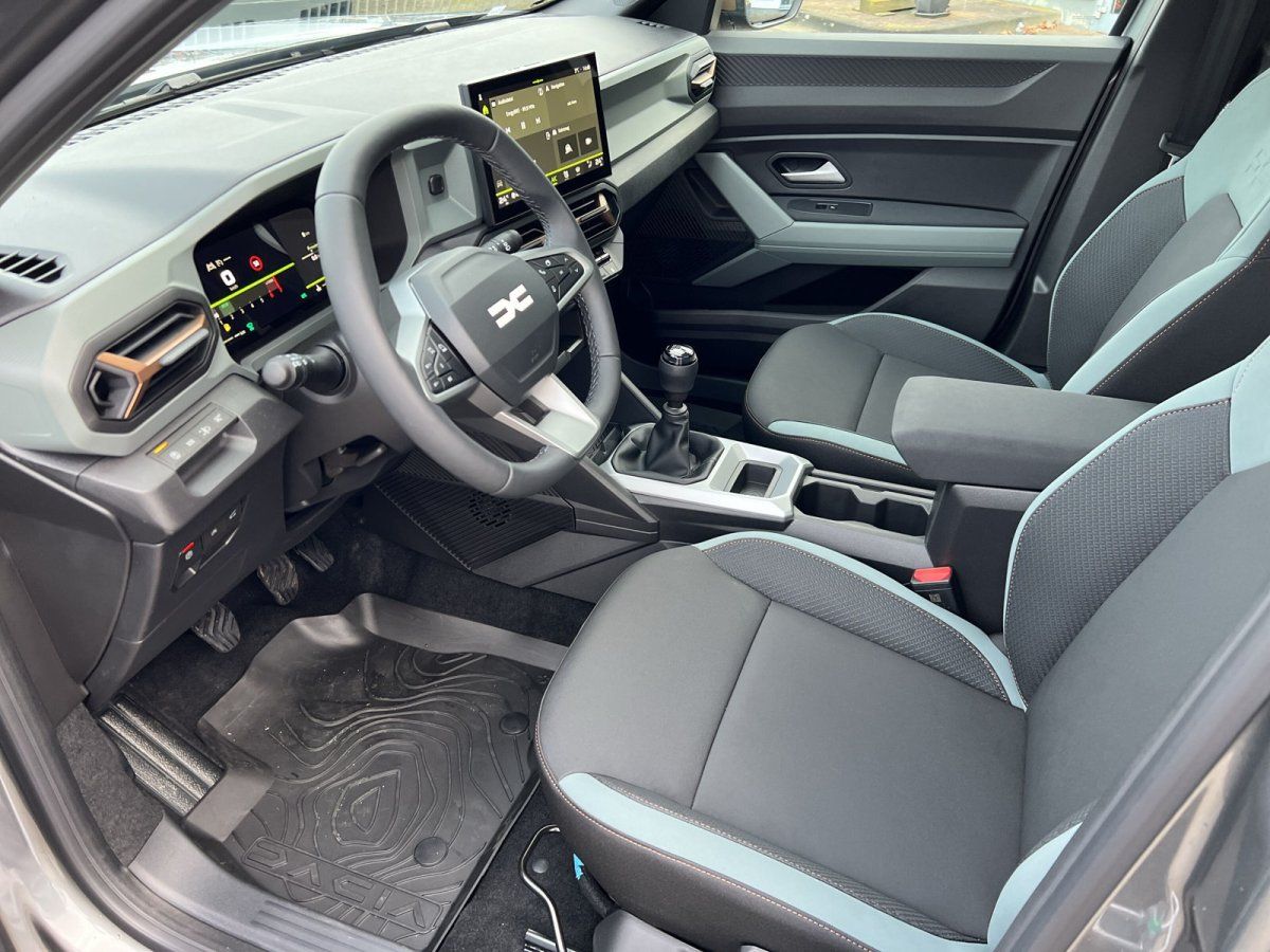 Dacia Innenraum mit Lenkrad, Digitalcockpit, Schaltgetriebe und zweifarbigen Sportsitzen