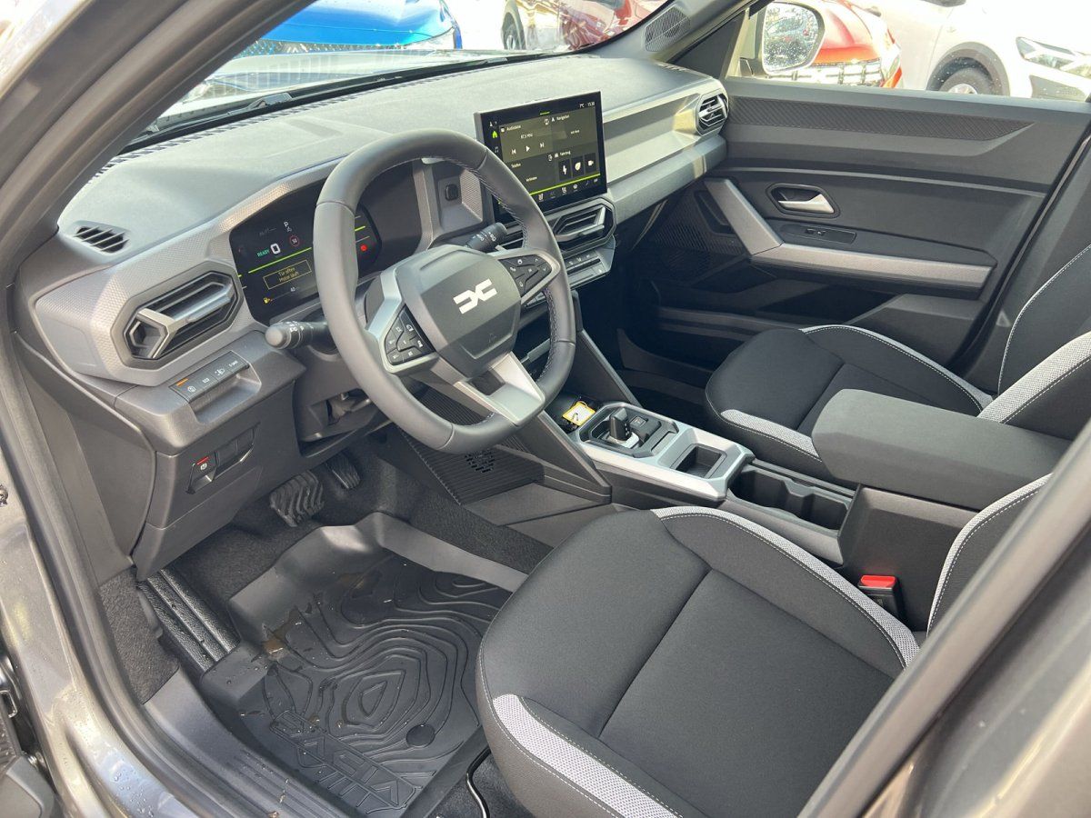 Dacia Innenraum mit Lenkrad, Infotainment-Display und schwarzen Sportsitzen
