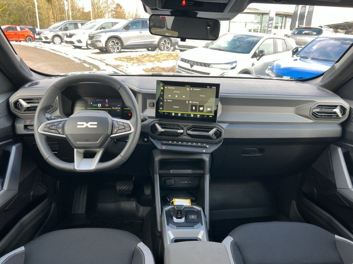 Dacia Innenraum mit Lenkrad, digitalem Cockpit und zentralem Touchscreen im Autohaus