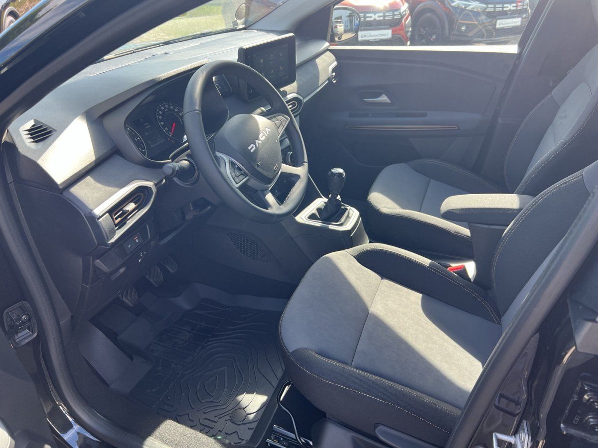 Dacia Innenraum mit Stoffsitzen, Lenkrad, Infotainment-Display und Schaltgetriebe im Autohaus