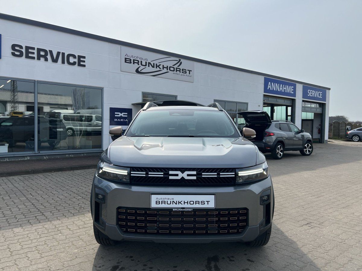 Grauer Dacia SUV Frontansicht im Autohaus Showroom mit großen Fenstern und modernem Interieur