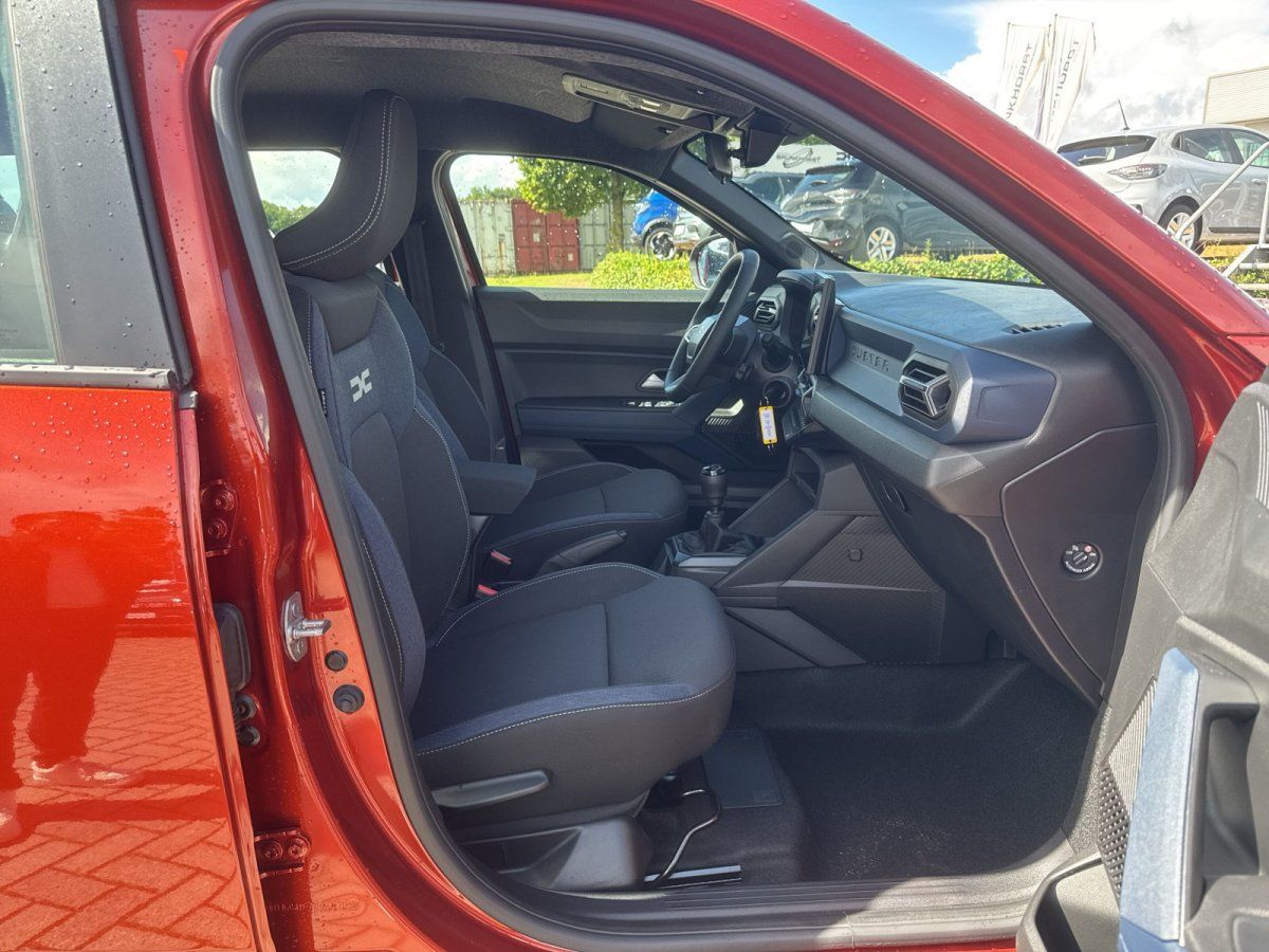 Dacia Sandero Innenraum mit schwarzen Stoffsitzen und modernem Cockpit in rotem Fahrzeug