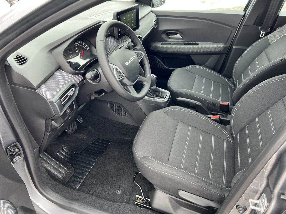 Dacia Innenraum Fahrerseite mit Lenkrad, Infotainment-Display und grauen Stoffsitzen