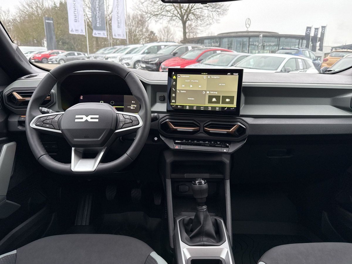 Dacia Innenraum mit digitalem Touchscreen, Lederlenkrad und Schaltgetriebe im Autohaus