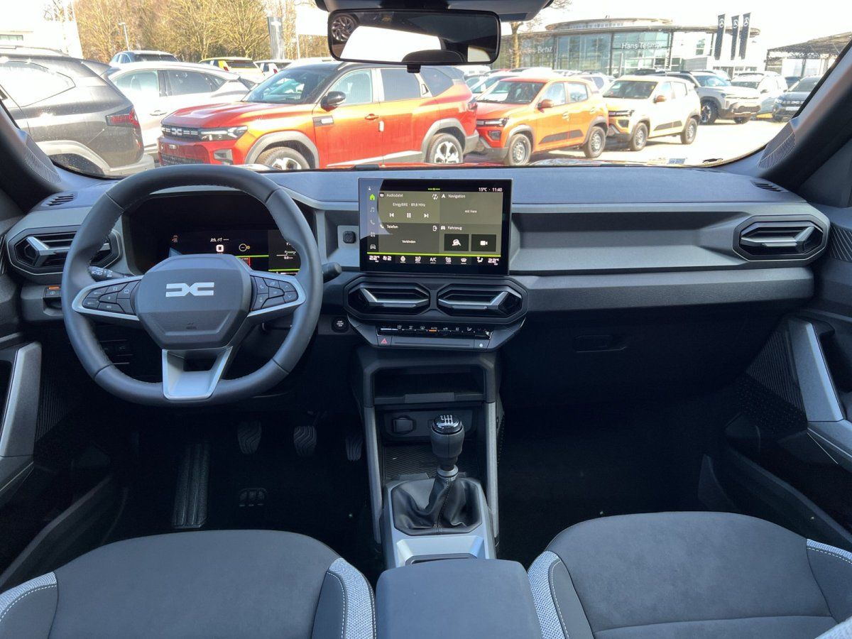 Dacia Innenraum mit Touchscreen, Schaltgetriebe und grauem Cockpit im Autohaus