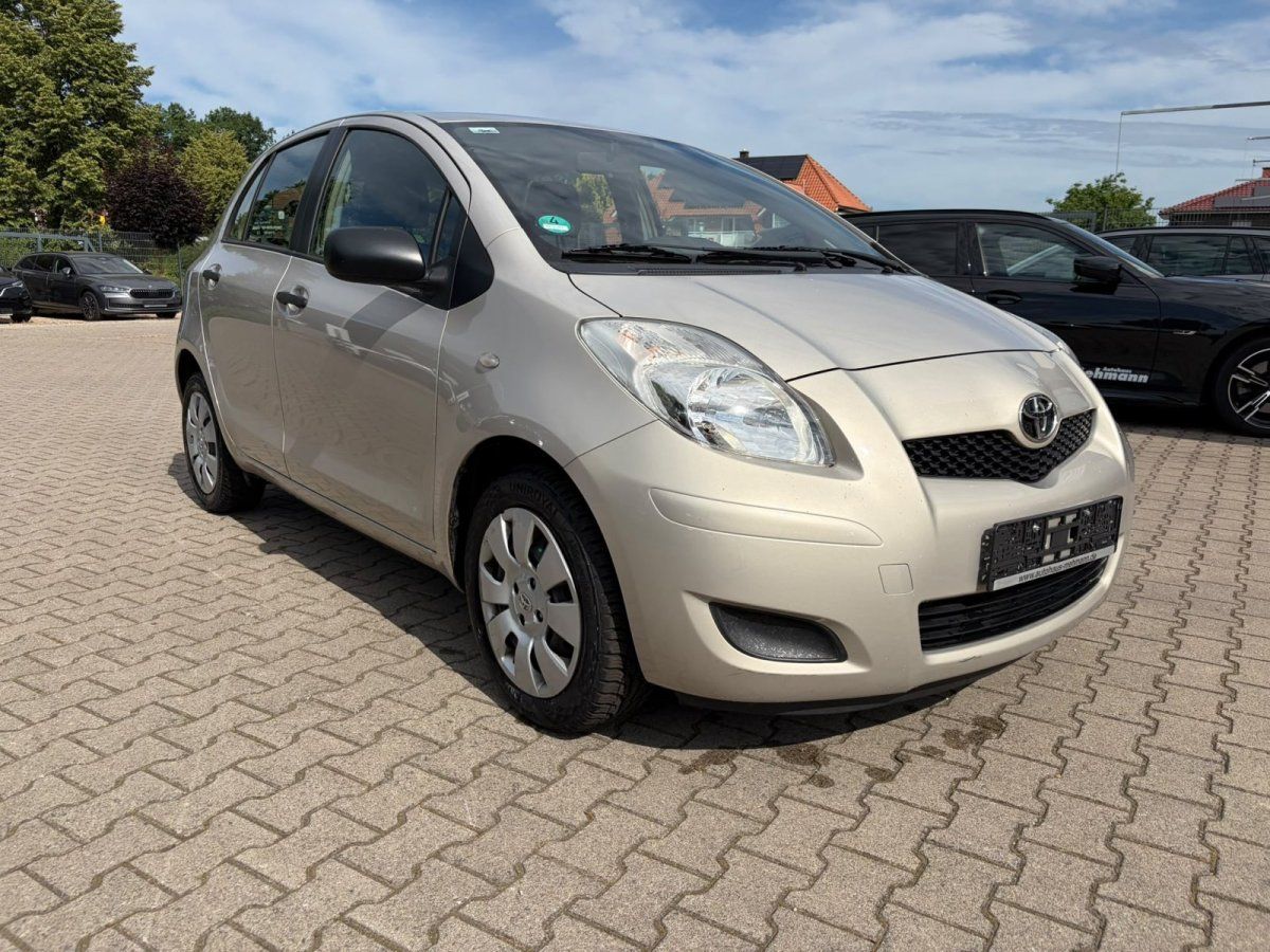 Toyota Yaris beige Frontansicht schraeg auf Pflasterstein