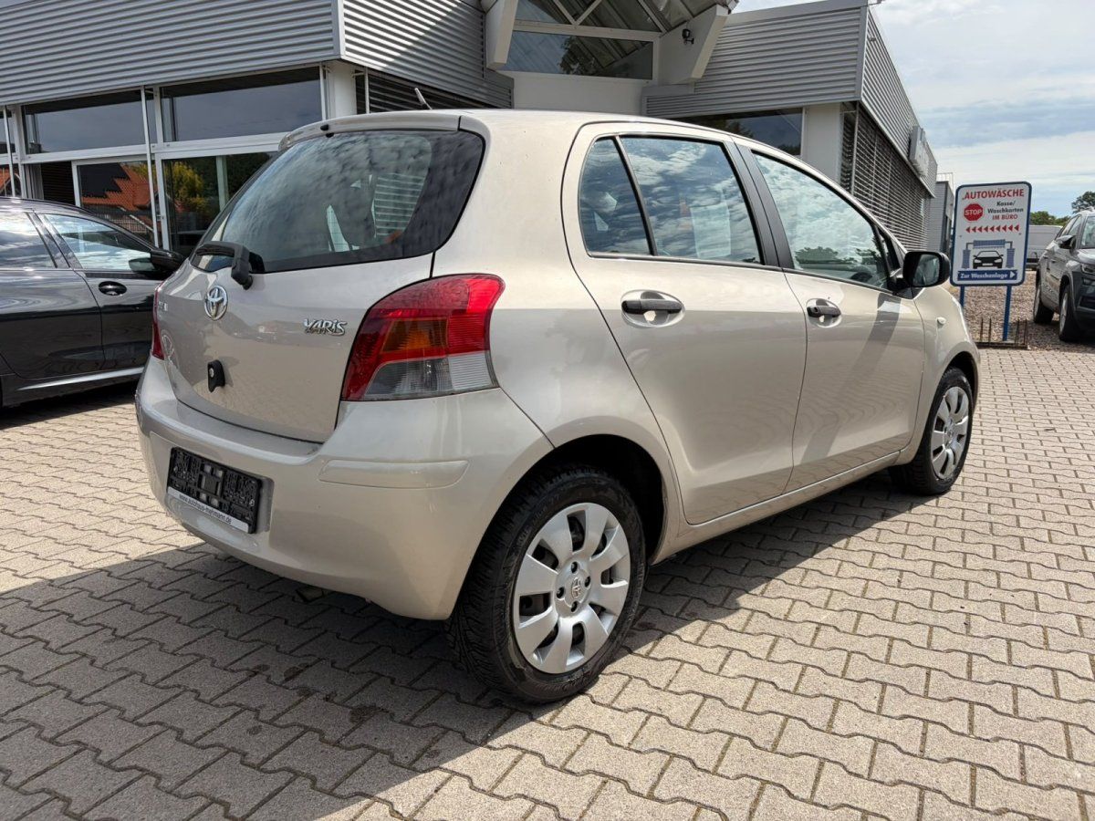 Toyota Yaris beige seitliche Heckansicht auf Händlerparkplatz