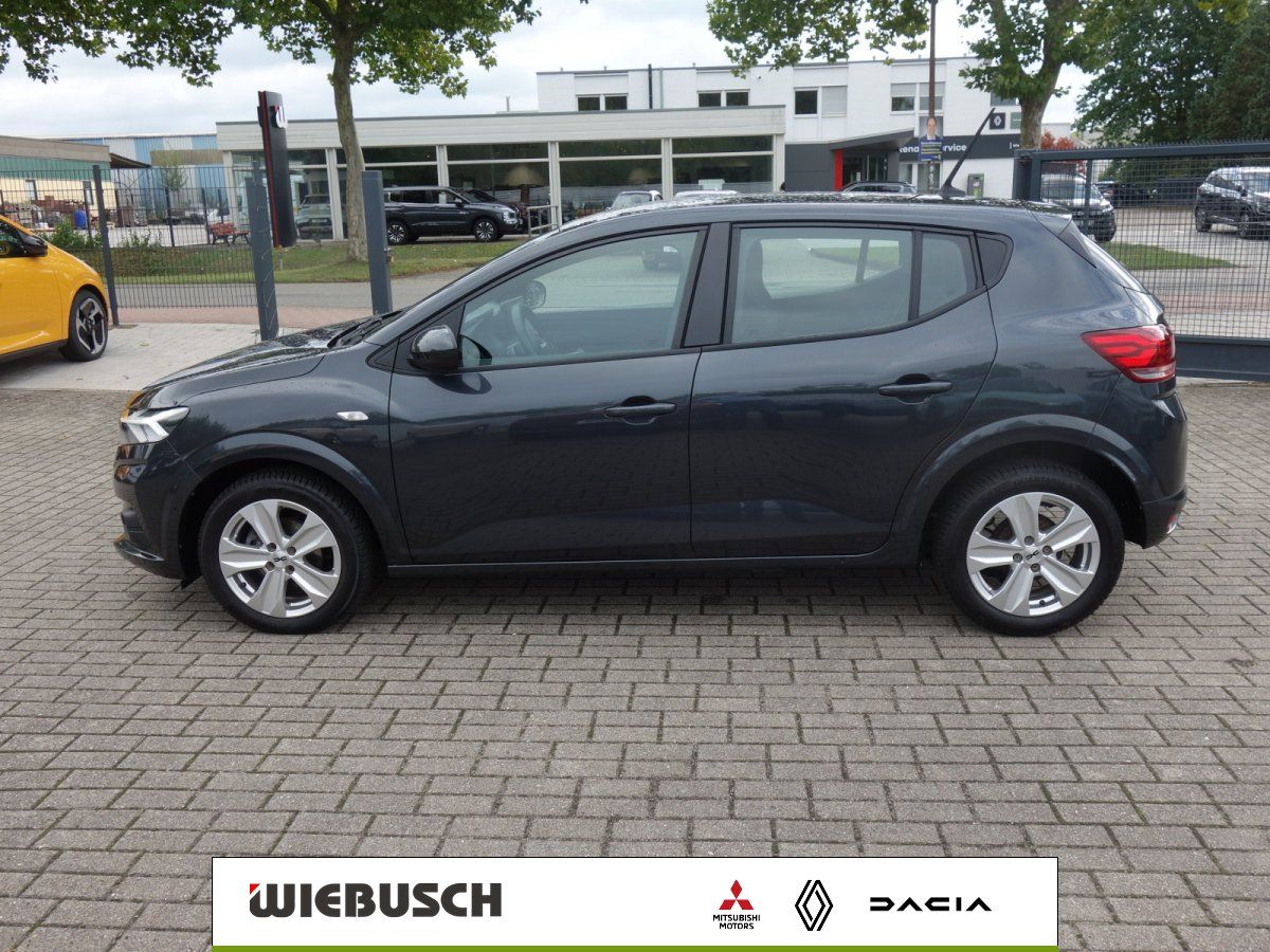Dacia Sandero grau metallic Seitenansicht auf Hof