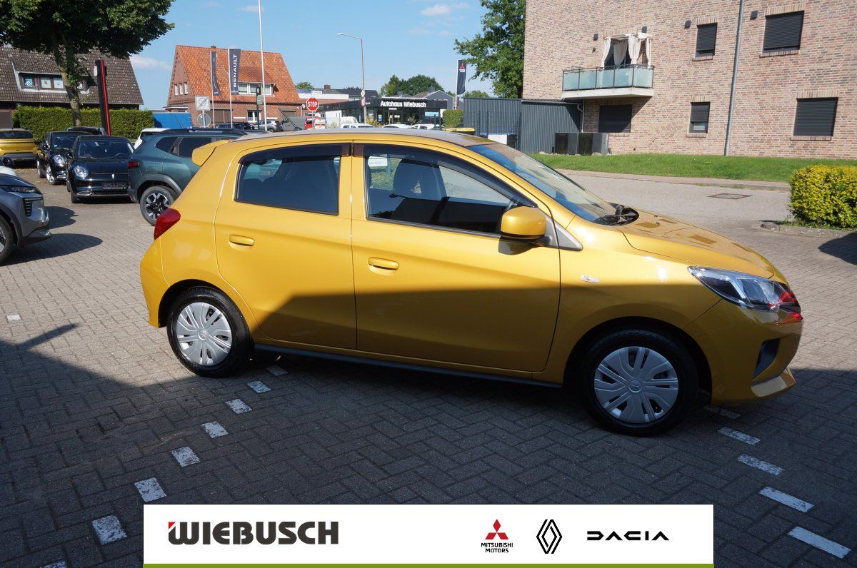 Gelber Mitsubishi Kleinwagen Seitenansicht vor Autohaus Wiebusch