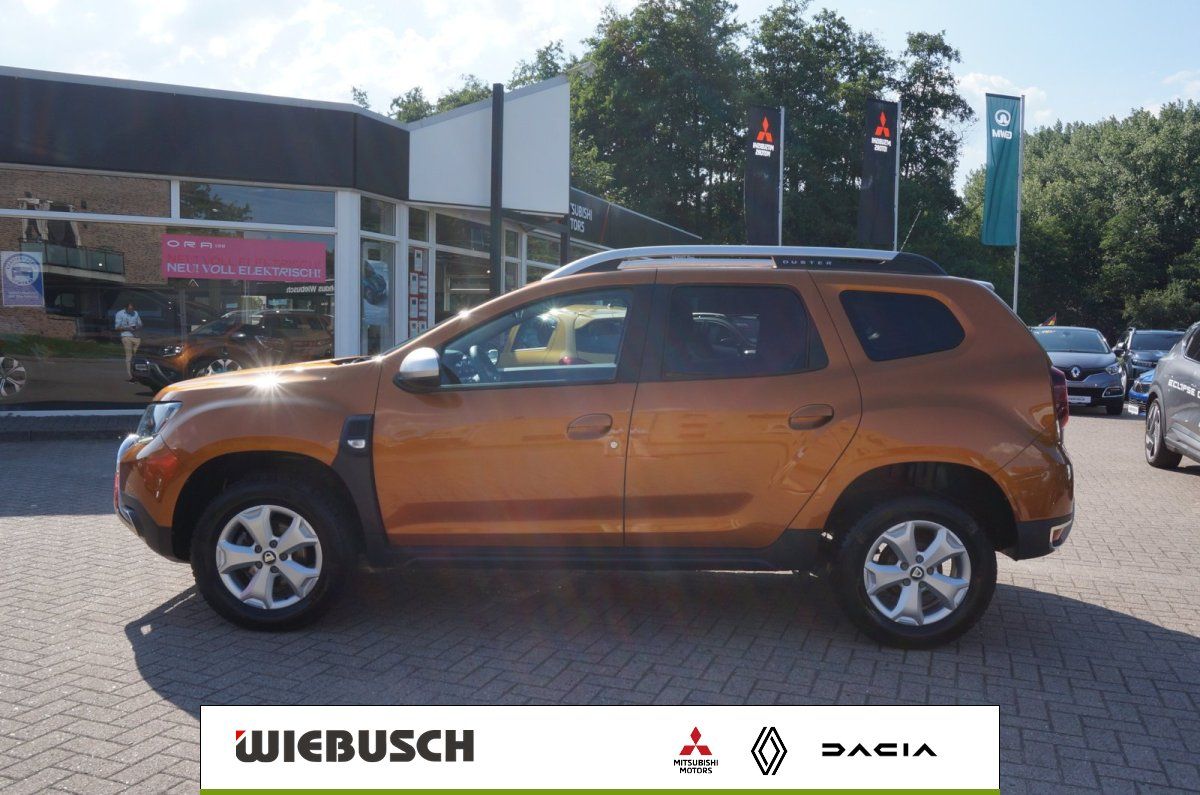 Dacia Duster orange Seitenansicht vor Autohaus Wiebusch
