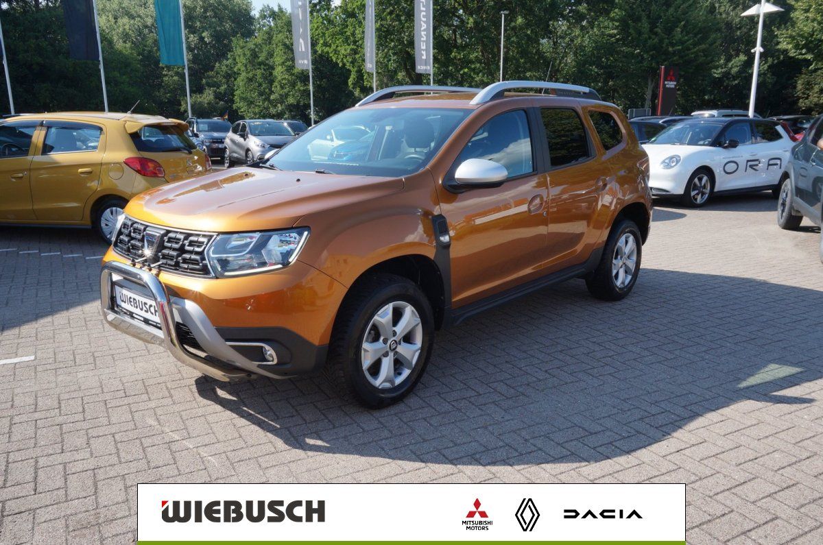 Dacia Duster orange Seitenansicht schräg vorne auf Autohaus-Parkplatz