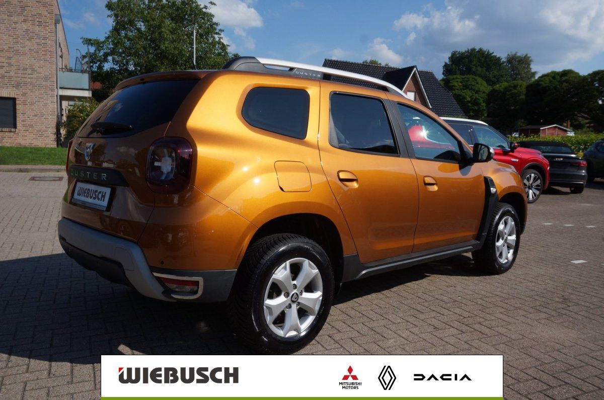 Dacia Duster orange Heckansicht mit Alufelgen auf Parkplatz
