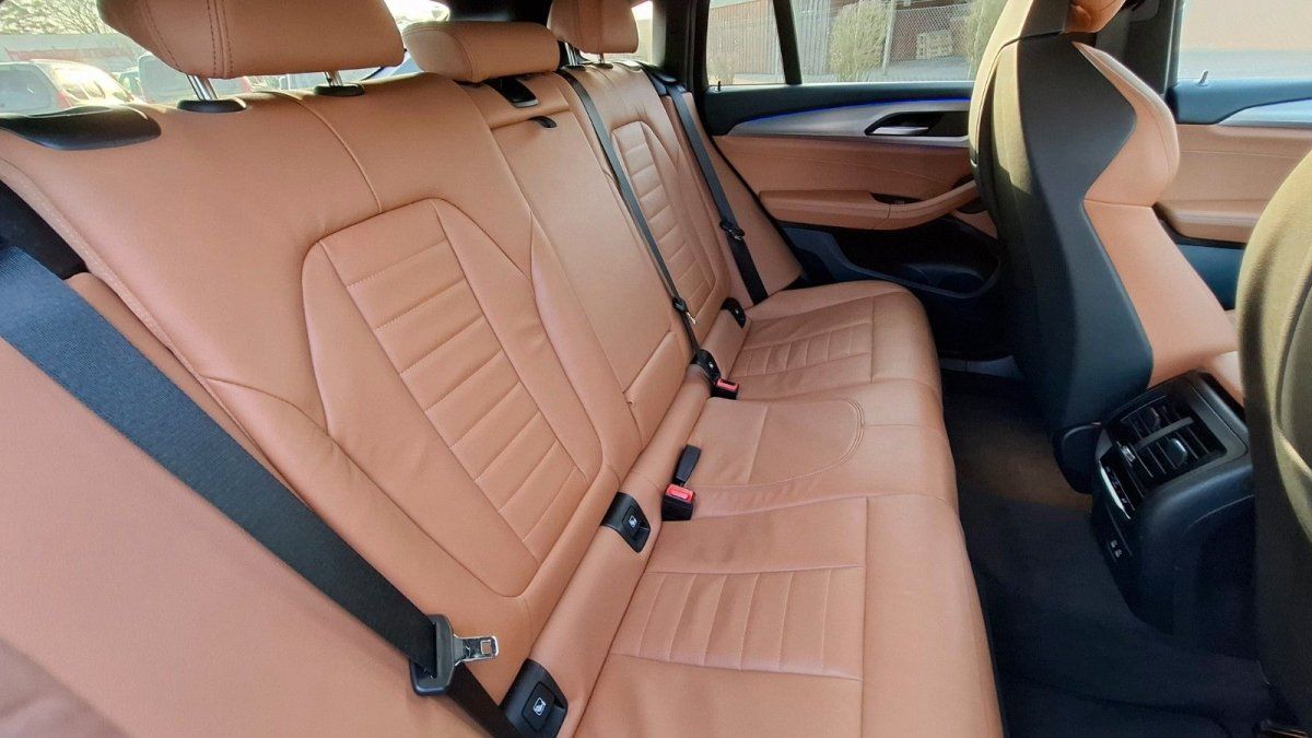 Luxuriöses Fahrzeug-Interieur mit cognacfarbenem Ledersitz im Fond und Sicherheitsgurten