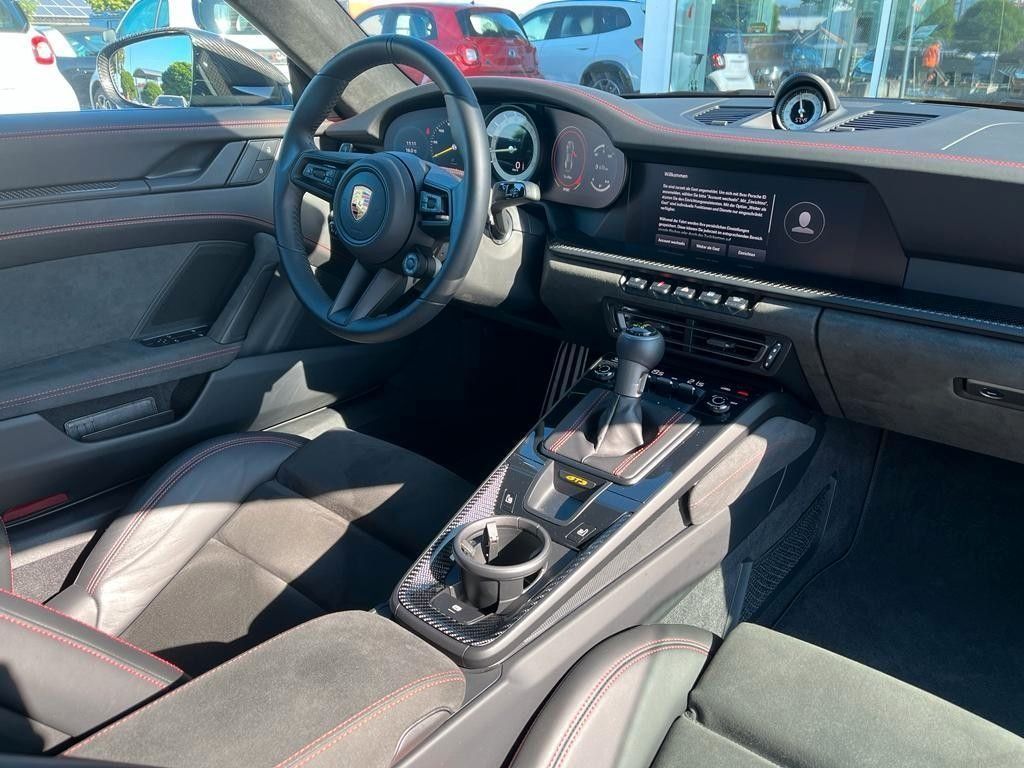 Porsche 911 Innenraum mit Ledersitze, Sportlenkrad und digitales Cockpit in dunklem Showroom