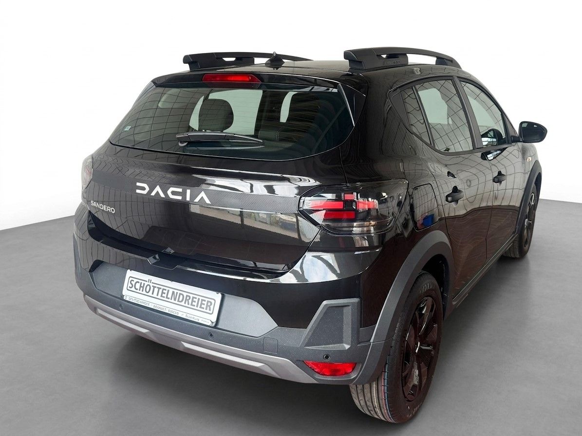 Dacia Sandero dunkelgrau metallic Heckansicht mit Dachträger und schwarzen Felgen