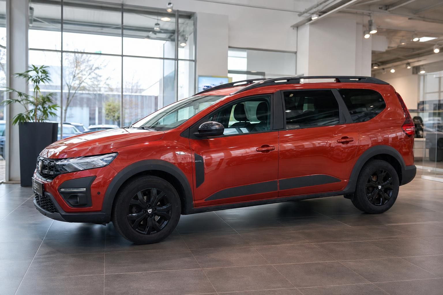 Roter Dacia SUV Schrägansicht von vorne - 7-Sitzer Familienwagen im modernen Autohaus