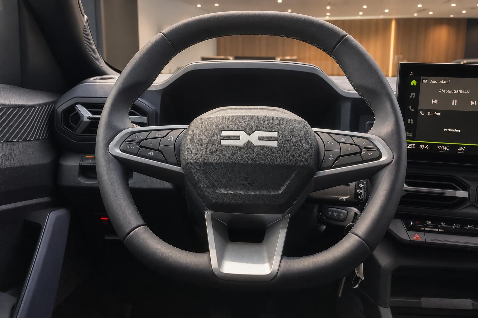 Lenkrad mit Multifunktionstasten und Infotainment Display im Cockpit